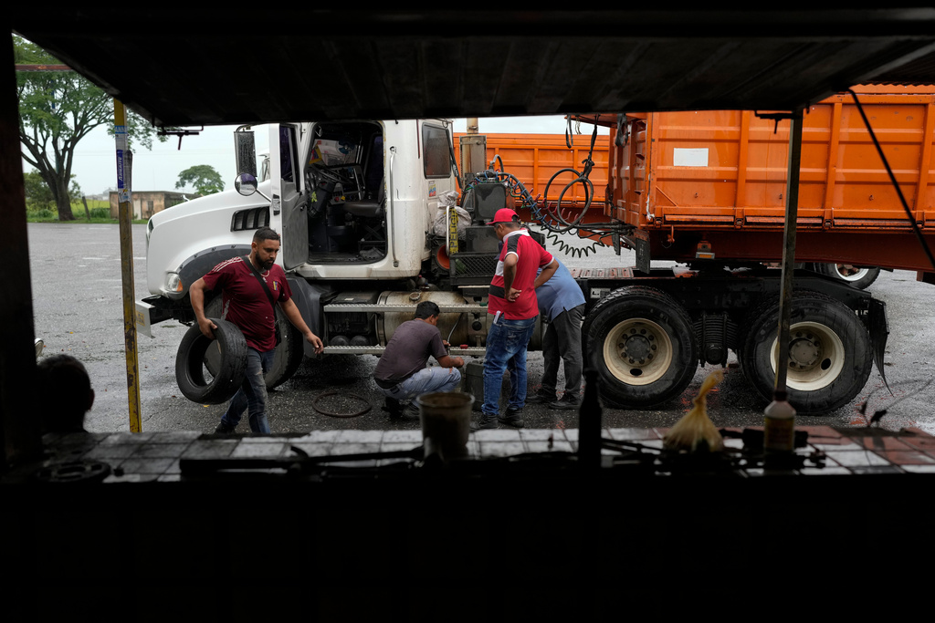Juan Guedez, left, works at a tire repair shop in Araure, Venezuela, June 12, 2025. He and his partner, Gabriela Villanueva, returned home after traveling by land from Chile to Mexico, where they decided to turn back following the Trump administration's decision to close the U.S. border to asylum seekers. (AP Photo/Matias Delacroix)