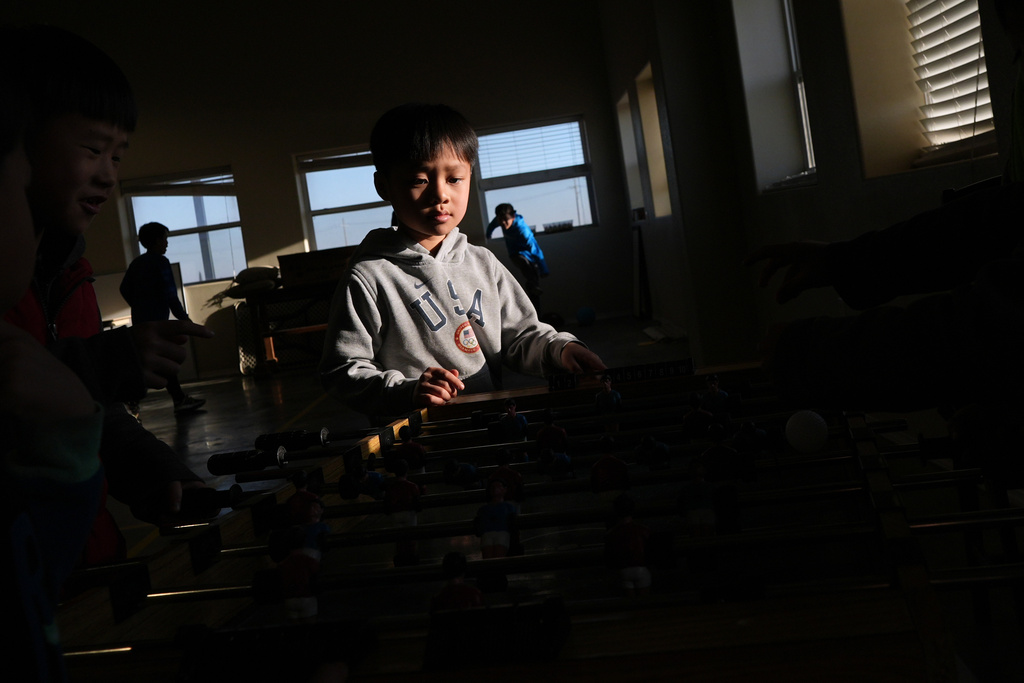 Nong Yitan plays foosball with other Mayflower Church kids inside the community hall in Midland, Texas, Jan. 18, 2025. (AP Photo/Rebecca Blackwell)