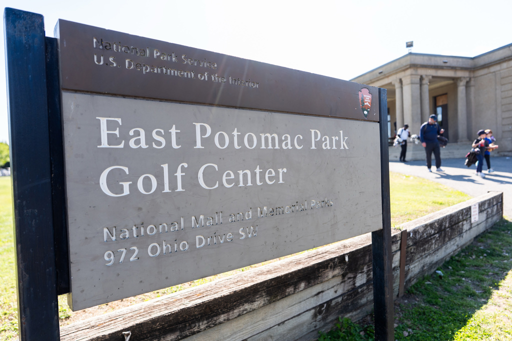 People walk past a sign at the entrance of East Potomac Golf Course, Sunday, May 3, 2026, in Washington. (AP Photo/Julia Demaree Nikhinson)
