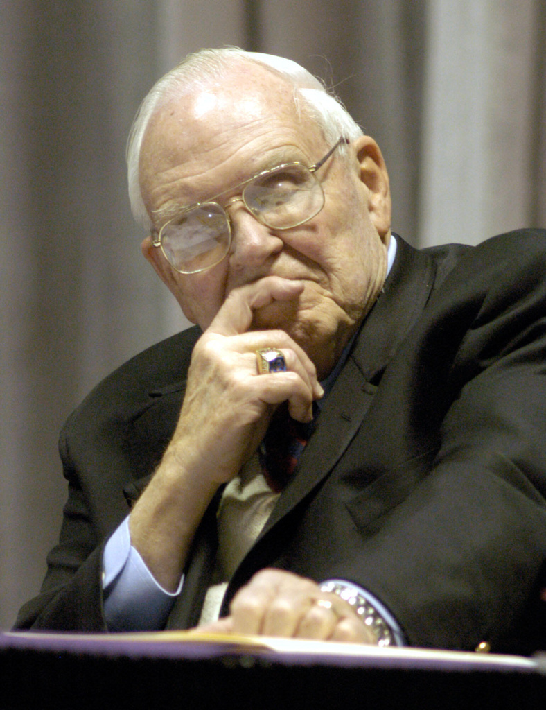 FILE - Roy Kramer, former commissioner , Southeastern Conference, listens to Mack Brown, Head Football Coach for The University of Texas, during his opening statement for the panel discussion for "Ethical Issues in College Athletics" in the Daniel-Meyer Coliseum on the Texas Christian University Campus, Thursday, Feb., 12, 2004. (AP Photo/David Pellerin, File)