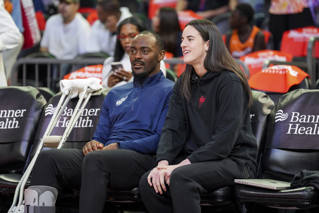 Indiana Fever guard Caitlin Clark, right, sits on the bench with Indiana Fever Player Development Coach Keith Porter before a WNBA basketball game against the Phoenix Mercury, Tuesday, Sept. 2, 2025, in Phoenix. (AP Photo/Samantha Chow)