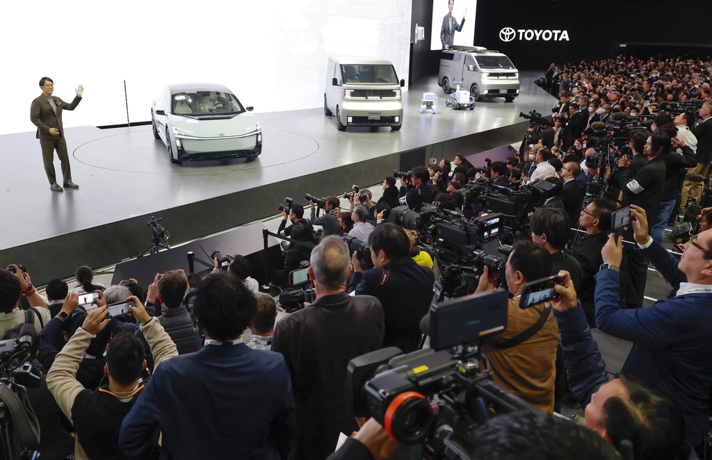 Toyota's President and CEO Koji Sato, left, speaks to the media beside Toyota vehicles on display at Tokyo Mobility Show during a press day at Tokyo Big Sight in Tokyo, on Wednesday, Oct. 29, 2025. (Daiki Katagiri/Kyodo News via AP)