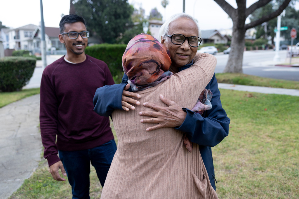 Mohammed Rashid, right, hugs his daughter in law Samiha Matin goodbye as his son, Faisal Rashid watches outside of their home in Pasadena Calif, Sunday, May 17, 2026, in Pasadena, Calif. (AP Photo/Ryan Sun)