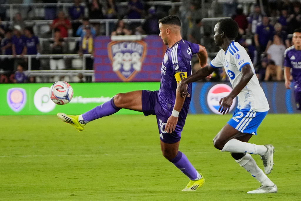 Orlando City midfielder Martin Ojeda, left, moves the ball past CF Montreal midfielder Victor Loturi during the second half of an MLS soccer match, Saturday, March 14, 2026, in Orlando, Fla. (AP Photo/John Raoux)