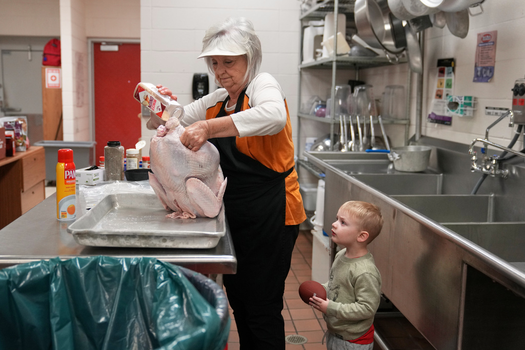 Kooper Keeland, 2, watches as his great-grandmother, high school cafeteria worker Shirley Mease, uses the kitchen at Reeds Spring High School to prepare 700 free Thanksgiving meals for community members Wednesday, Nov. 26, 2025, in Reeds Spring, Mo. (AP Photo/Jeff Roberson)