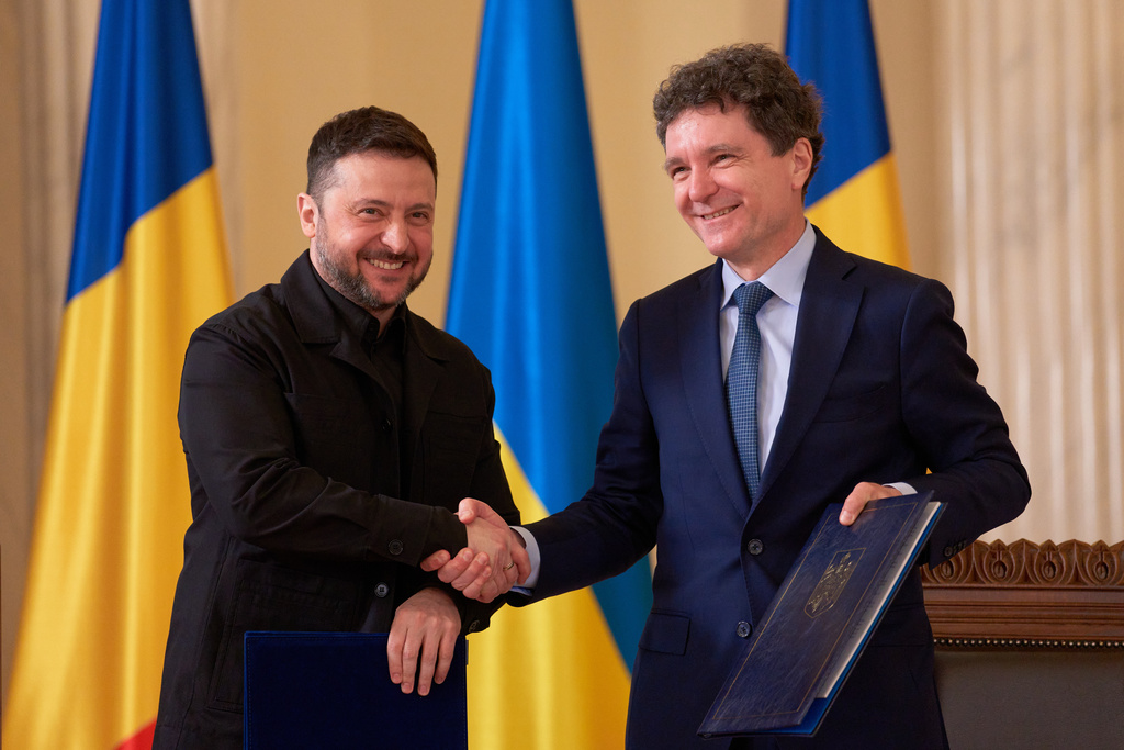 Ukrainian President Volodymyr Zelenskyy, left, shakes hands with Romanian President Nicusor Dan holding bilateral cooperation documents after a signing ceremony at the Cotroceni Presidential Palace in Bucharest, Romania, Thursday, March 12, 2026. (AP Photo/Andreea Alexandru)