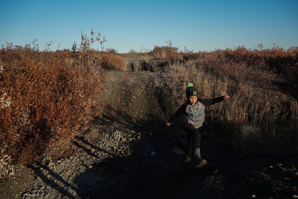 James Schaeffer, 7, plays on a road where thawing permafrost has caused the ground to warp in Kotzebue, Alaska, Friday, Sept. 26, 2025. (AP Photo/Annika Hammerschlag)