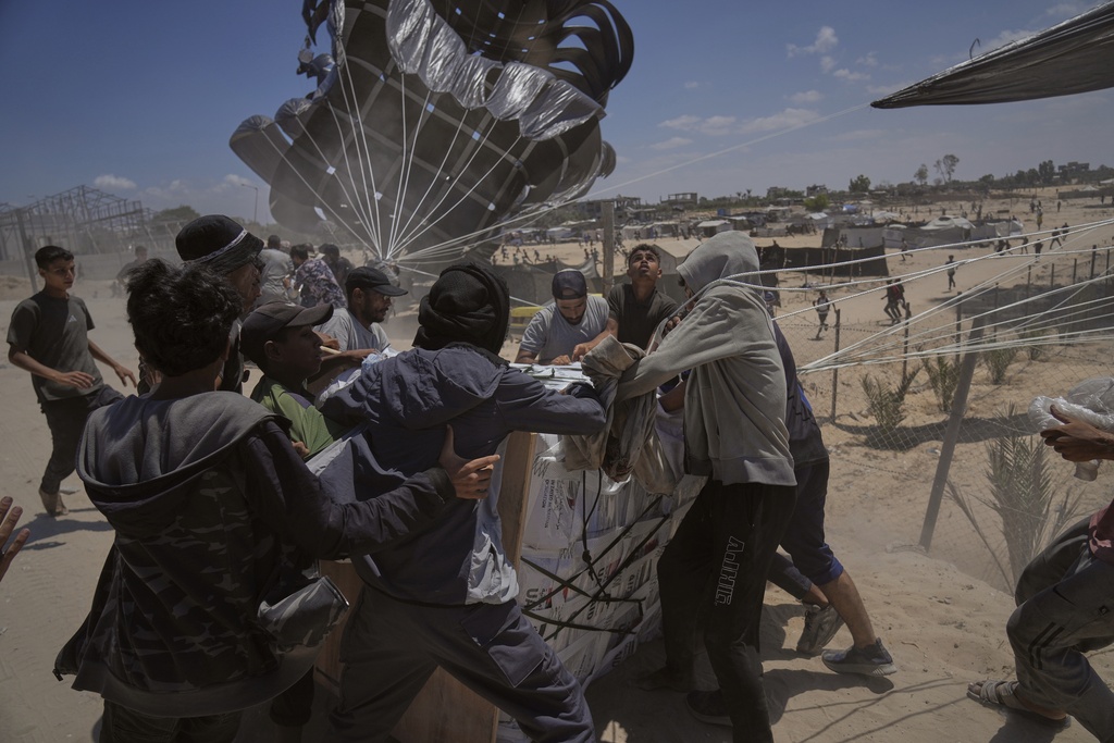 FILE - Palestinians rush to collect humanitarian aid airdropped by parachutes into Deir al-Balah, central Gaza Strip, Tuesday, Aug. 5, 2025. (AP Photo/Abdel Kareem Hana, File)