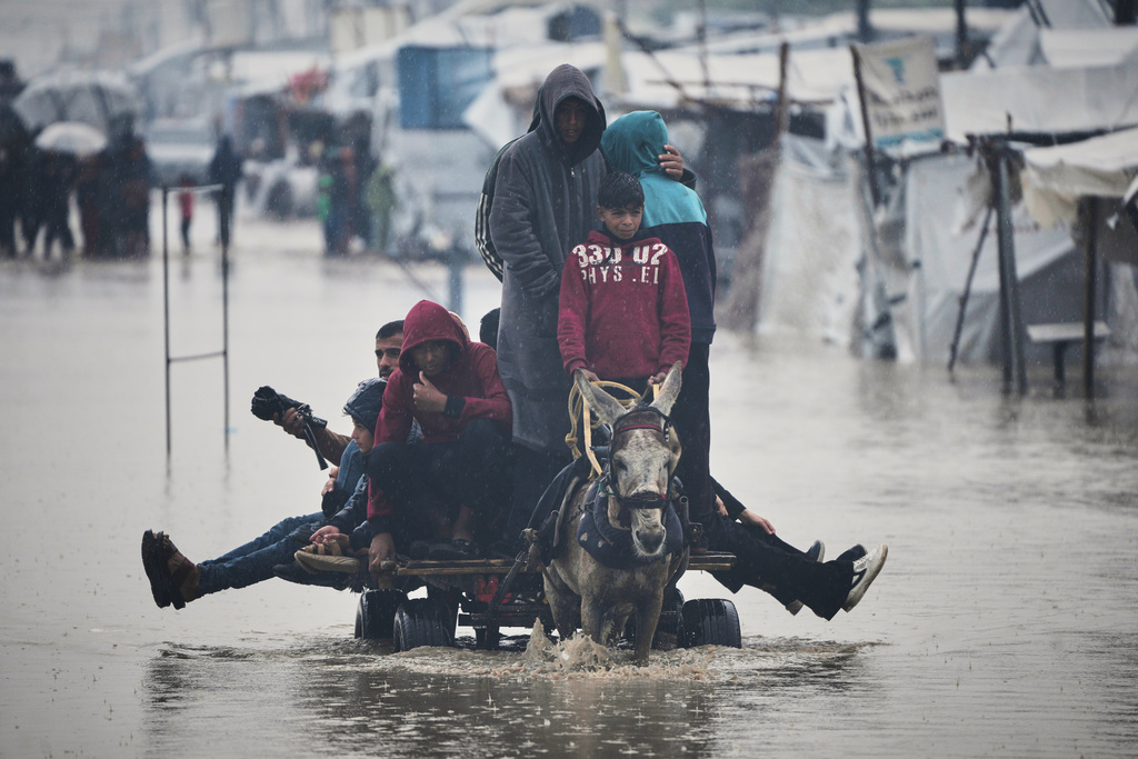 Palestinians cross a flooded street following heavy rain in Khan Younis, southern Gaza Strip, Thursday, Dec. 11, 2025. (AP Photo/Abdel Kareem Hana)