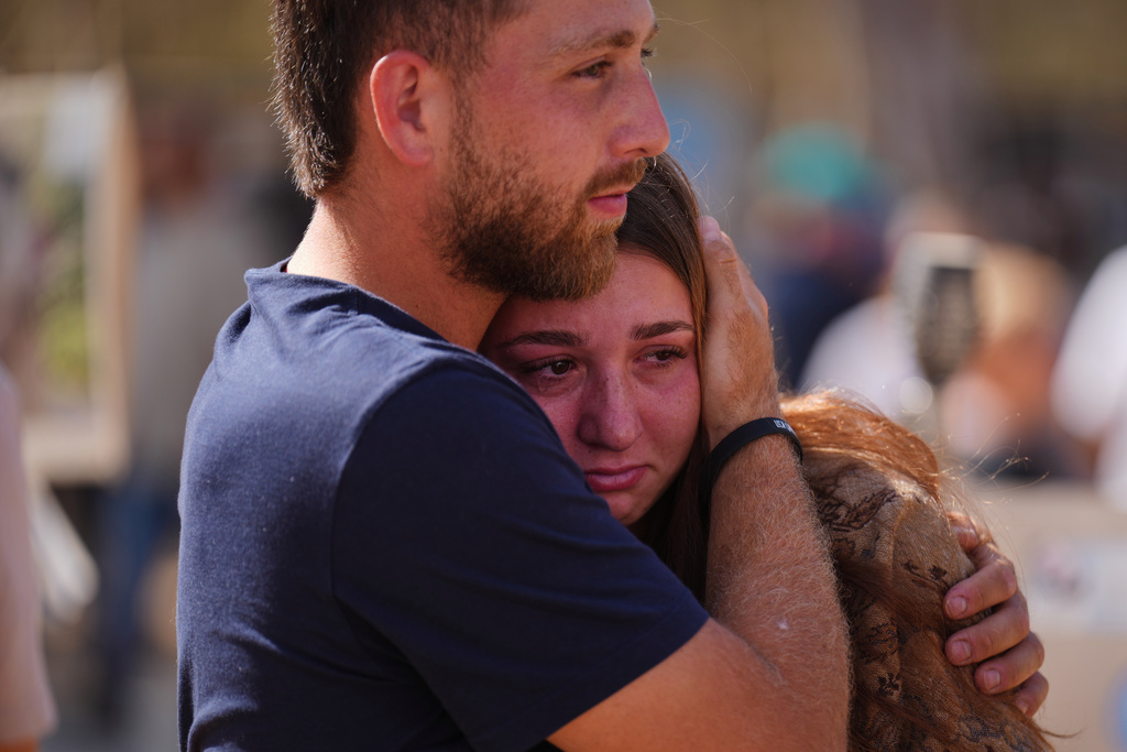 People embrace during a memorial marking two years anniversary of the Oct. 7, 2023 deadly Hamas attack on Israel, at the site of the Nova music festival near Kibbutz Reim in southern Israel, where hundreds of revelers were killed and abducted in the assault, Tuesday, Oct. 7, 2025. (AP Photo/Ariel Schalit)