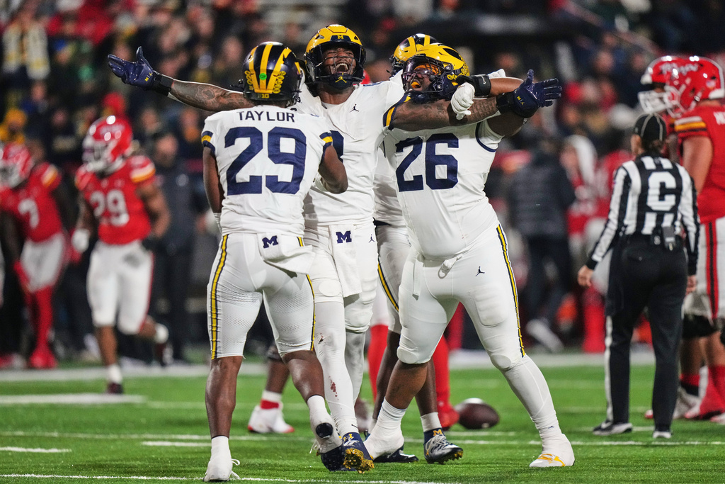 Michigan defensive end Derrick Moore, center, celebrates after a sack against Maryland quarterback Malik Washington to force a turnover during the second half of an NCAA college football game, Saturday, Nov. 22, 2025, in College Park, Md. (AP Photo/Stephanie Scarbrough)