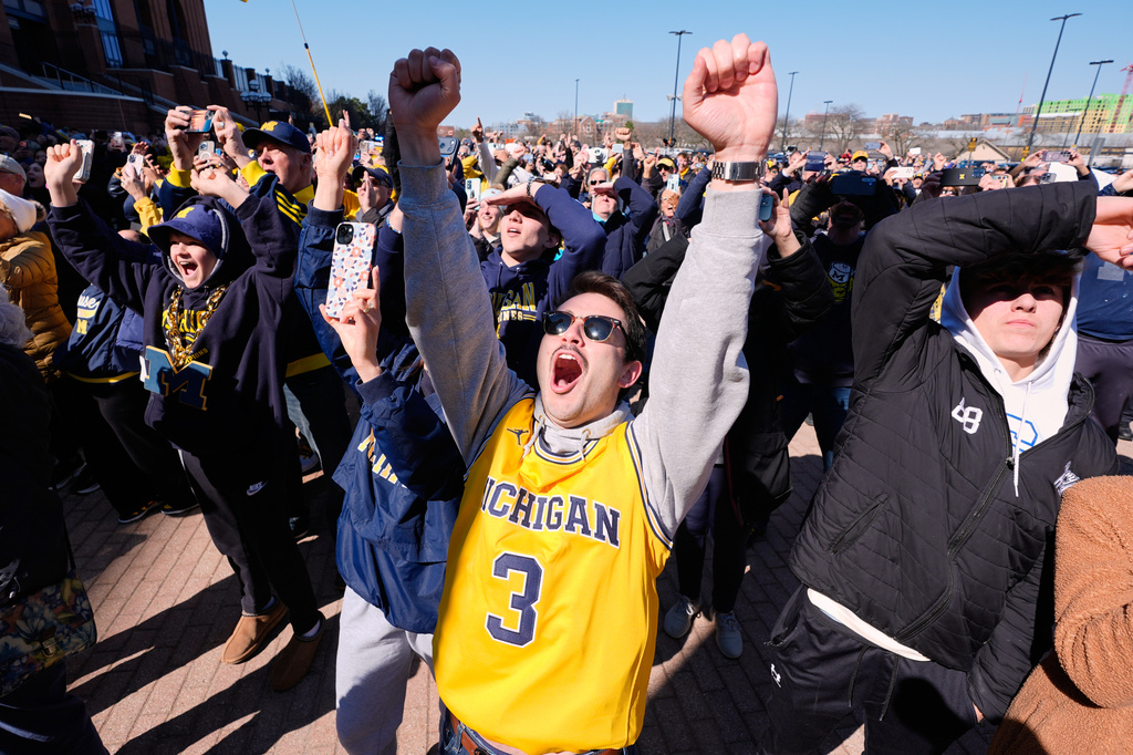 Michigan fans including Nick Weykamp celebrate winning the NCAA basketball tournament championship with the team as they return to campus Tuesday, April 7, 2026, in Ann Arbor, Mich. (AP Photo/Paul Sancya)