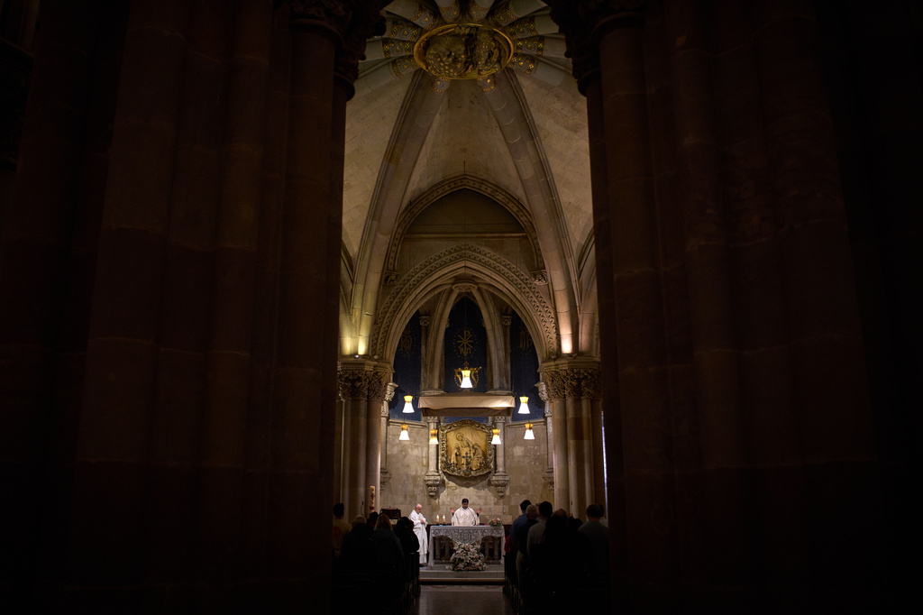 A priest celebrates Mass in the crypt of Antoni Gaudí beneath the Sagrada Familia while crowds of visitors fill the basilica above in Barcelona, Spain, May 15, 2026. (AP Photo/Emilio Morenatti)