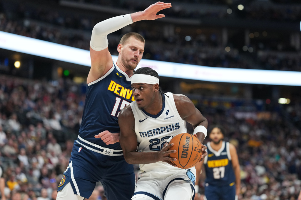 Memphis Grizzlies forward Taylor Hendricks, front, drives to the rim as Denver Nuggets center Nikola Jokić defends in the first half of an NBA basketball game Wednesday, April 8, 2026, in Denver. (AP Photo/David Zalubowski)