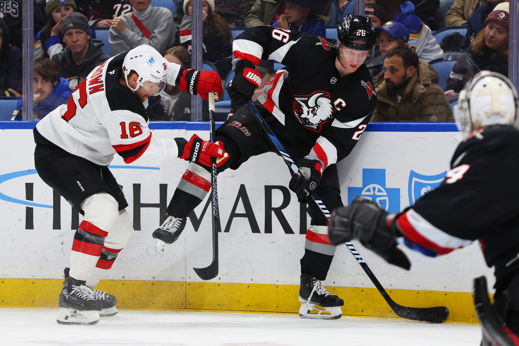 Buffalo Sabres defenseman Rasmus Dahlin (26) is checked by New Jersey Devils right wing Connor Brown (16) during the second period of an NHL hockey game, Friday, Nov. 28, 2025, in Buffalo, N.Y. (AP Photo/Jeffrey T. Barnes)