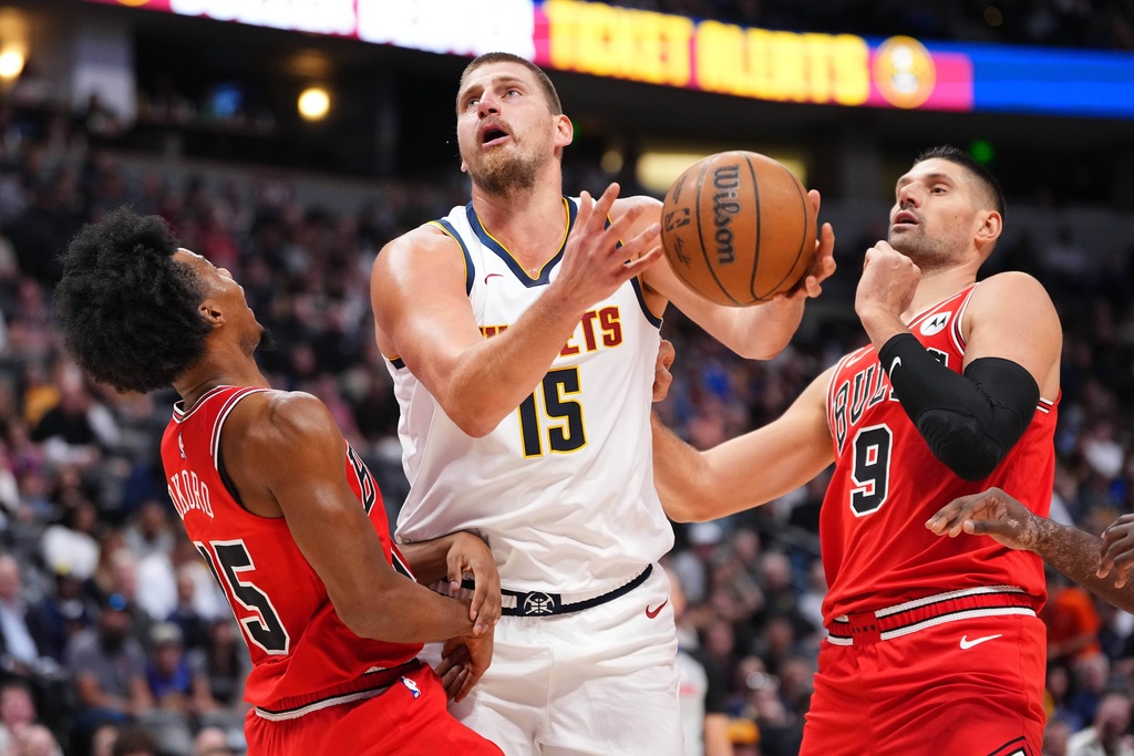 Denver Nuggets center Nikola Jokić (15) is fouled by Chicago Bulls forward Isaac Okoro (35) as Chicago Bulls center Nikola Vučević (9) looks on during the first half of a preseason NBA basketball game Tuesday, Oct. 14, 2025, in Denver. (AP Photo/Jack Dempsey)