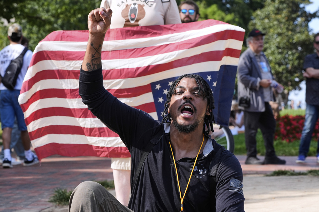 Dionte Carter raises his fist during a protest of President Donald Trump's federal takeover of policing of the District of Columbia, Saturday, Aug. 16, 2025, near the White House in Washington. (AP Photo/Alex Brandon)