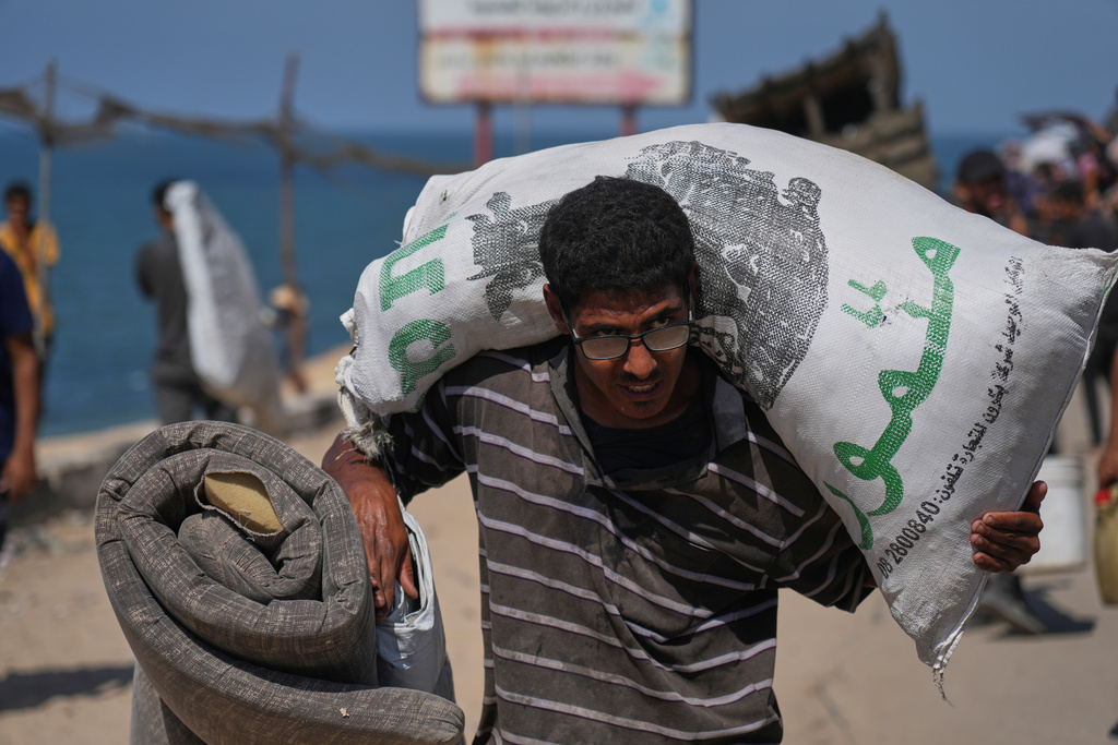 A displaced Palestinian flees northern Gaza Strip, carrying his belongings along the coastal road, near Wadi Gaza, Tuesday, Sept. 23, 2025. (AP Photo/Abdel Kareem Hana)