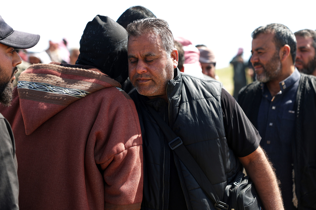Hamad al-Jalib is comforted by mourners during the funeral of his wife and four of his five children, who were killed in Israeli strikes in Beirut earlier this week, during their funeral in the village of al-Sour, Deir al-Zour province, northeastern Syria, Saturday, April 11, 2026. (AP Photo/Ghaith Alsayed)
