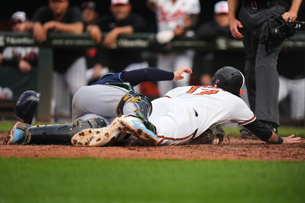 Baltimore Orioles' fielder Colton Cowser (17) scores against Tampa Bay Rays catcher Hunter Feduccia, left, during the 12th inning of a baseball game, Monday, May 25, 2026, in Baltimore. (AP Photo/Stephanie Scarbrough)