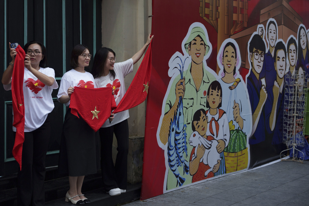 Women take picture with Vietnam's national flag as the nation celebrating Vietnam's 80th National Day in Hanoi, Friday, Aug. 29, 2025. (AP Photo/Vincent Thian)