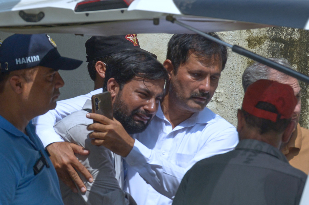 A father, center, of a victim in a fire, is comforted as his child's coffin is carried outside a hospital in Islamabad, Pakistan, Wednesday, Aug. 26, 2026. (AP Photo/M.A. Sheikh)