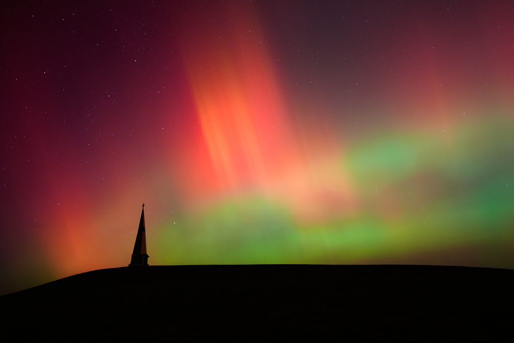 The northern lights fill the sky behind the Saint Joseph the Woodworker Shrine, Nov. 11, 2025, near Valley Falls, Kan. (AP Photo/Charlie Riedel, File)