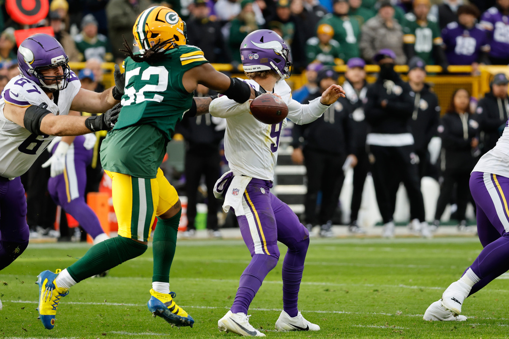Minnesota Vikings quarterback J.J. McCarthy (9) looks to pass as Green Bay Packers defensive end Rashan Gary (52) tries to tackle during the second half of an NFL football game Sunday, Nov. 23, 2025, in Green Bay, Wis. (AP Photo/Mike Roemer)