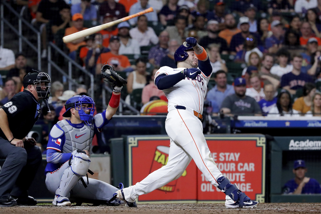 Houston Astros's Victor Caratini, right, loses his bat on his swing in front of Texas Rangers catcher Kyle Higashioka, center, and umpire Cory Blaser, left, during the seventh inning of a baseball game Tuesday, Sept. 16, 2025, in Houston. (AP Photo/Michael Wyke)