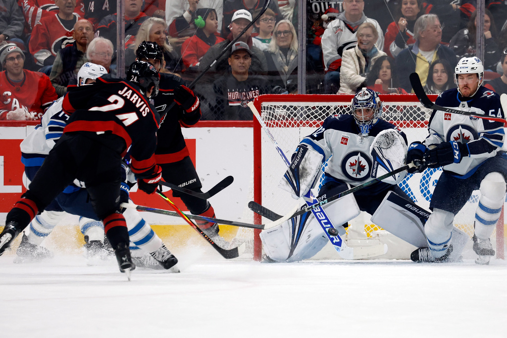 Carolina Hurricanes' Seth Jarvis (24) shoots the puck past Winnipeg Jets goaltender Thomas Milic (32) for a goal during the first period of an NHL hockey game in Raleigh, N.C., Friday, Nov. 28, 2025. (AP Photo/Karl DeBlaker)