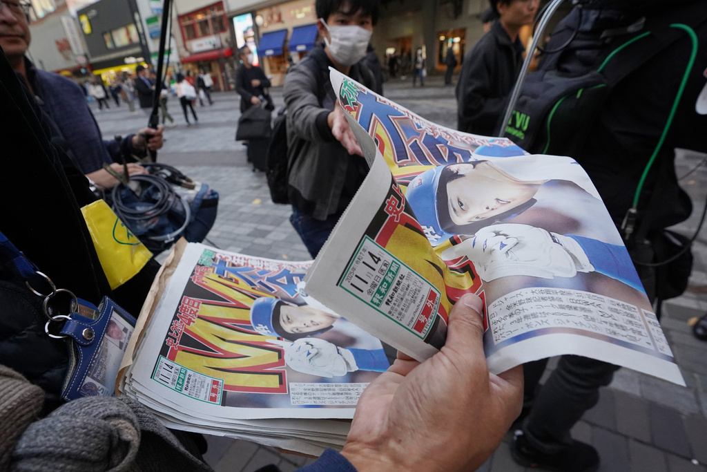 Staff of Japan's sports newspaper, The Hochi Shimbun, hands over a copy of the extra issue published after the Los Angeles Dodgers Shohei Ohtani won a Most Valuable Player award, to passersby in Tokyo, Friday, Nov. 14, 2025. (AP Photo/Koji Ueda)