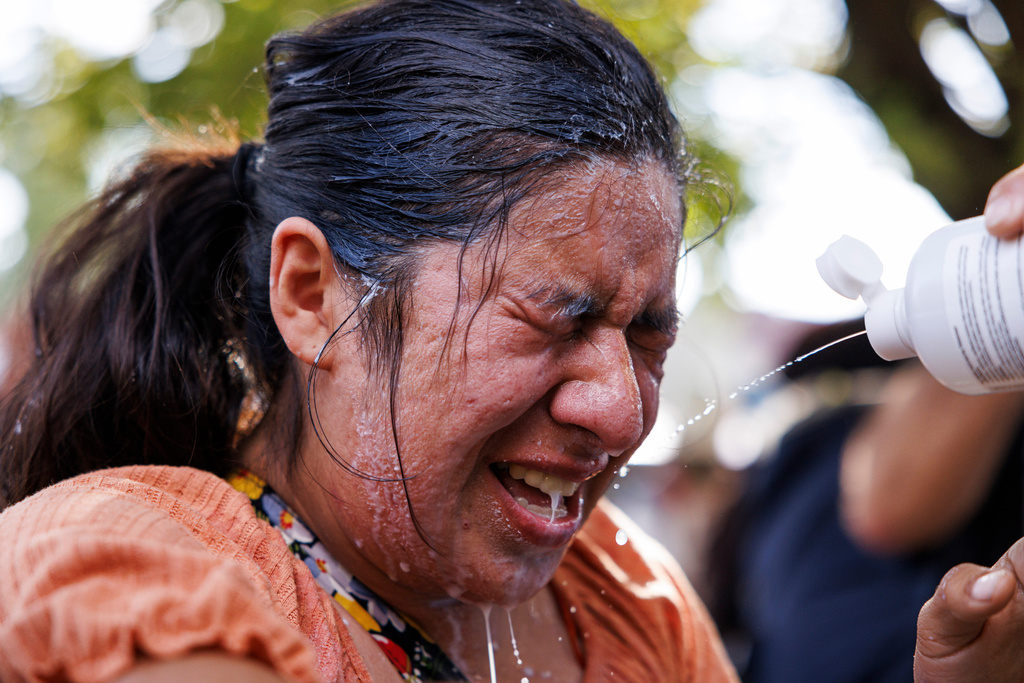 A protestor is doused with milk, water, and saline after tear gas in the Brighton Park neighborhood of Chicago, on Saturday, Oct. 4, 2025, after protesters learned that U.S. Border Patrol shot a woman Saturday morning on Chicago's Southwest Side. (Anthony Vazquez/Chicago Sun-Times via AP)