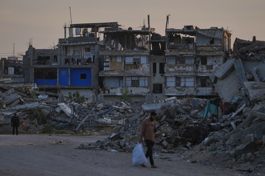 Palestinians walk along a street surrounded by buildings destroyed during Israeli air and ground operations in Khan Younis, southern Gaza Strip, Thursday, April 9, 2026. (AP Photo/Abdel Kareem Hana)