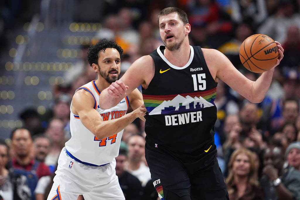 Denver Nuggets center Nikola Jokić, right, fields a pass as New York Knicks guard Landry Shamet, left, defends in the first half of an NBA basketball game Friday, March 6, 2026, in Denver. (AP Photo/David Zalubowski)