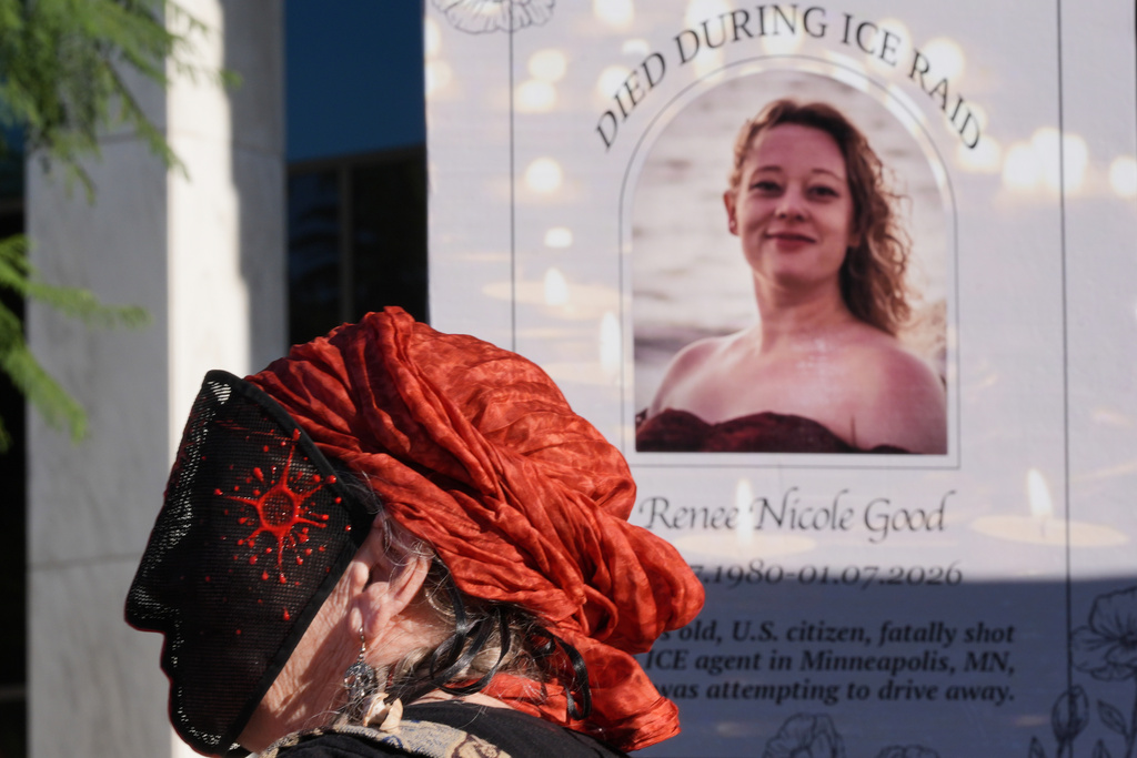 A demonstrator wears a mask in front of an image of Renee Good during a protest to denounce the Trump administration's immigration enforcement polices Friday, Jan. 16, 2026, in Los Angeles. (AP Photo/Jae C. Hong)