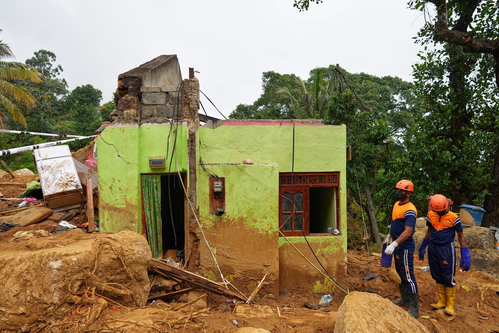 Sri Lankan army rescuers stand next to the remnants of a destroyed row of living quarters where tea plantation workers stayed after a landslide following Cyclone Ditwah at Craighead Estate in Nawalapitiya, Sri Lanka, Thursday, Dec. 11, 2025. (AP Photo/Eranga Jayawardena)