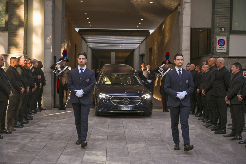 Staff of Giorgio Armani Spa gather outside the Armani/Teatro in Milan, northern Italy, as the hearse with the casket of designer Giorgio Armani, who died Thursday at age 91, leaves, Sunday, Sept. 7, 2025. (AP Photo/Nicola Marfisi)