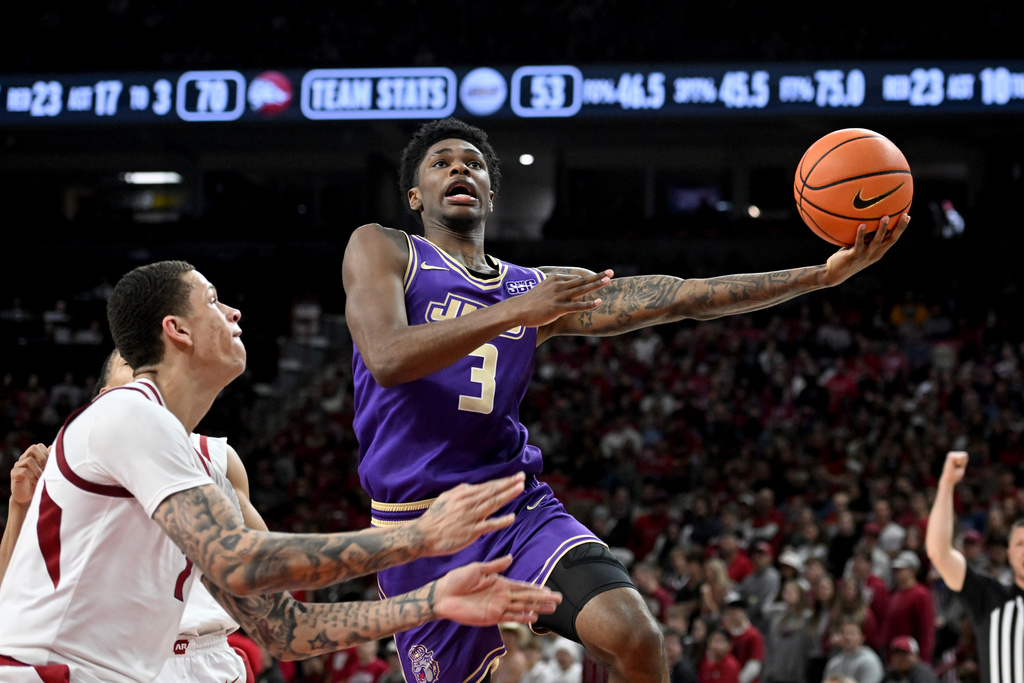 James Madison forward Eddie Ricks III (3) drives past Arkansas forward Trevon Brazile (7) during an NCAA college basketball game Monday, Dec. 29, 2025, in Fayetteville, Ark. (AP Photo/Michael Woods)