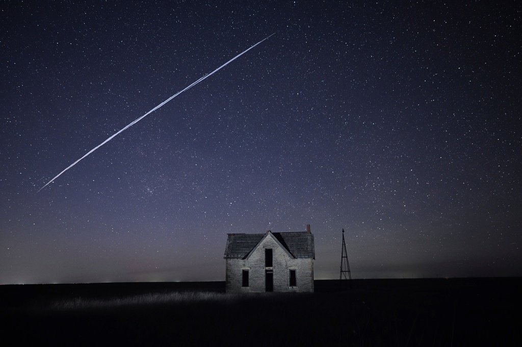 FILE - In this long exposure photo, a string of SpaceX StarLink satellites passes over an old stone house near Florence, Kan., on May 6, 2021. (AP Photo/Reed Hoffmann, File)