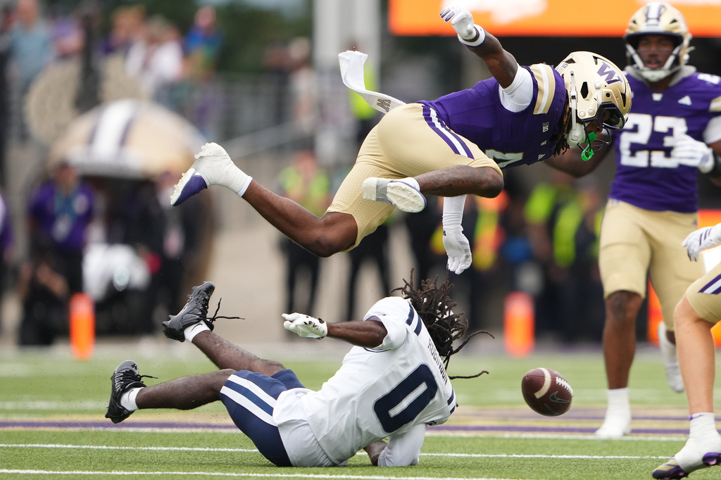Washington safety Rylon Dillard-Allen knocks the helmet off of Utah State wide receiver Javon Robinson (0) after Robinson missed a pass during the second half of an NCAA college football game Saturday, Sept. 12, 2026, in Seattle. (AP Photo/Lindsey Wasson)