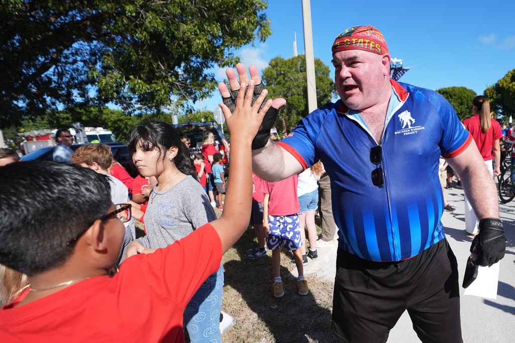 U.S. Army and Marine veteran William Hansen high-five students as wounded veterans ride in the annual Florida Keys Soldier Ride organized by the Wounded Warrior Project, Friday, Jan. 9, 2026, in Islamorada, Fla. (AP Photo/Lynne Sladky)