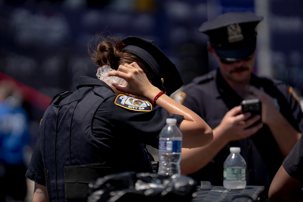 FILE - A police officer holds ice to their neck to try and stay cool following the 2026 Nathan's Famous Fourth of July hot dog eating contest at Coney Island in the Brooklyn borough of New York, July 4, 2026. (AP Photo/Anna Connors, File)