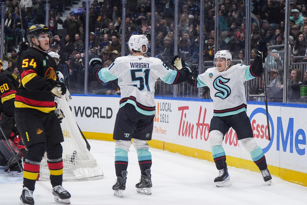 Seattle Kraken's Bobby McMann, right, and Shane Wright celebrate McMann's goal as Vancouver Canucks' Aatu Raty (54) looks on during the first period of an NHL hockey game, in Vancouver, on Saturday, March 14, 2026. (Darryl Dyck/The Canadian Press via AP)