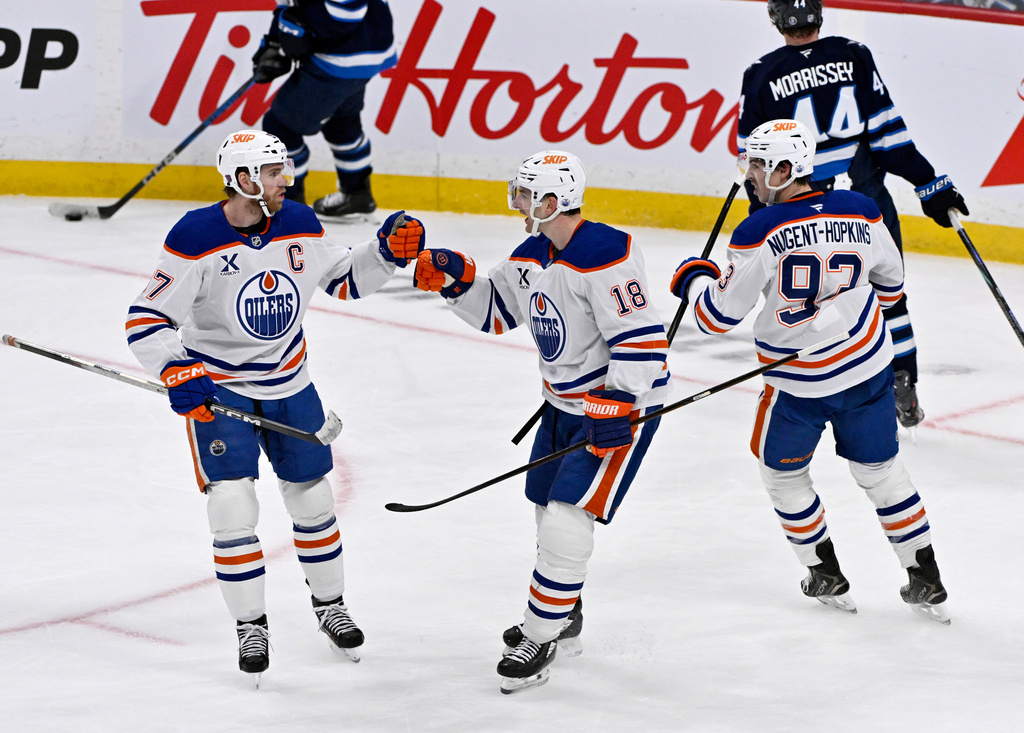 Edmonton Oilers' Zach Hyman (18) celebrates his empty net goal against the Winnipeg Jets with teammates Connor McDavid (97) and Ryan Nugent-Hopkins (93) during the third period of an NHL game in Winnipeg, Monday Dec. 29, 2025. (Fred Greenslade/The Canadian Press via AP)