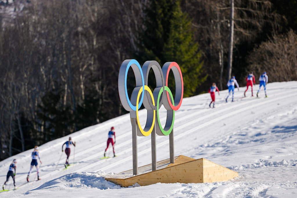 FILE - Athletes ski past the Olympic rings during the cross country skiing women's 50km mass start classic at the 2026 Winter Olympics, in Tesero, Italy, Feb. 22, 2026. (AP Photo/Matthias Schrader, File)