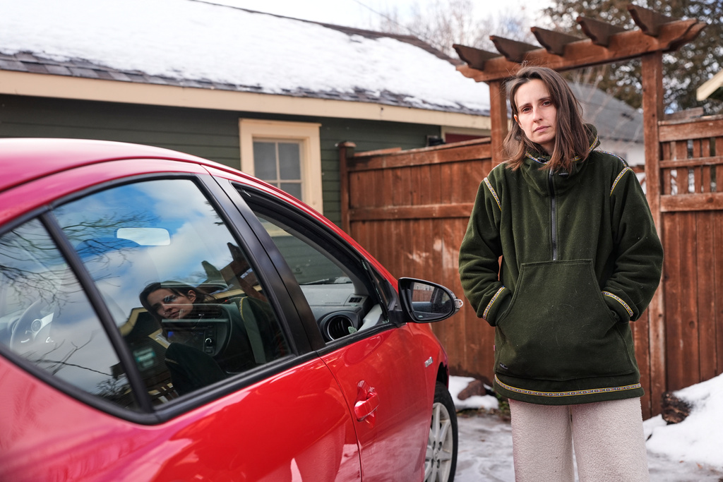 Patty O'Keefe, a U.S. citizens who was arrested while following federal agents' vehicles and briefly held at a federal facility in Minneapolis, stands next to her car showing that her front driver's side window was smashed in, Tuesday, Jan. 13, 2026. (AP Photo/Jen Golbeck)