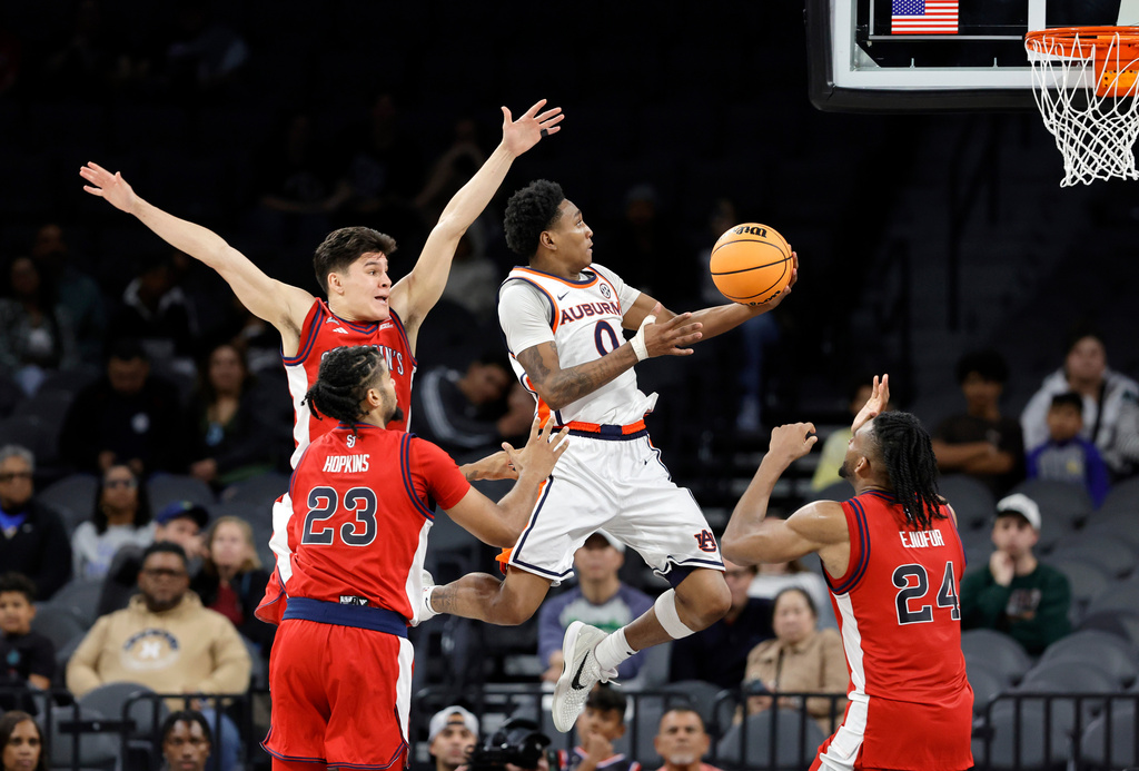Auburn guard Tahaad Pettiford (0) heads to the basket as St. John's guard Dylan Darling, back left, forward Bryce Hopkins (23) and Zuby Ejiofor (24) defend during the second half of an NCAA college basketball game in the Players Era tournament Wednesday, Nov. 26, 2025, in Las Vegas. (AP Photo/Steve Marcus)