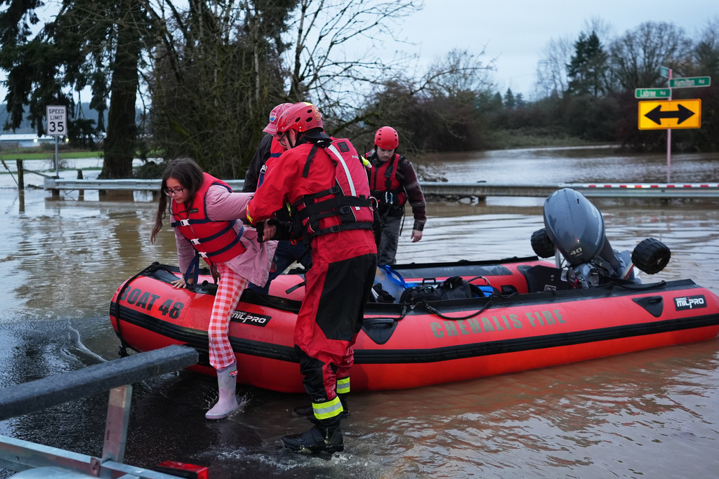 Maery Schine, 11, is helped out of a rescue boat by rescue workers with Chehalis Fire after evacuating with her father Patric, second from left, following flooding after heavy rains in the region Tuesday, Dec. 9, 2025, in Chehalis, Wash. (AP Photo/Lindsey Wasson)