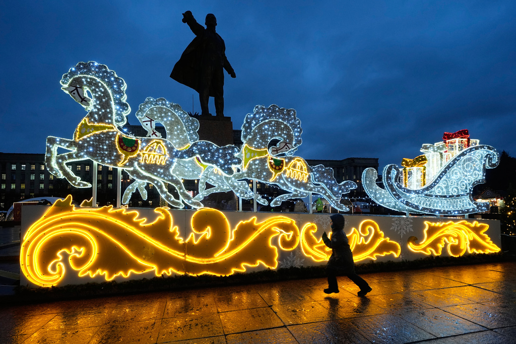 A boy runs at a Christmas fair opened prior to Christmas and New Year festivities in St. Petersburg, Russia, Thursday, Dec. 25, 2025, with a statue of Soviet Union founder Vladimir Lenin in the background. (AP Photo/Dmitri Lovetsky)