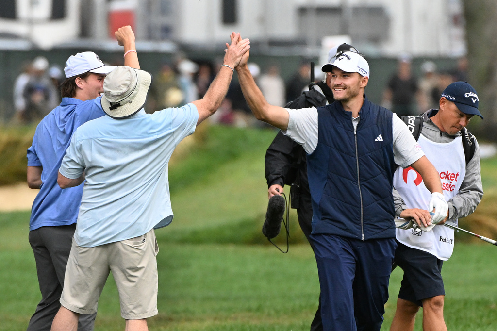 Rasmus Hojgaard, front right, of Denmark, is congratulated by fans after he hit an eagle on the fourth hole during the final round of the Rocket Classic golf tournament Sunday, Aug. 2, 2026, in Detroit. (AP Photo/Jose Juarez)